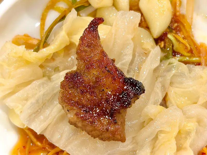 양념갈비 한 점을 쌈에 싸서 먹는 모습