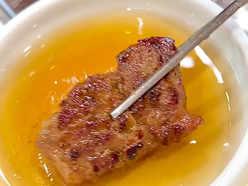 잘 구워진 양념갈비 한 점을 소스에 찍어 먹는 모습