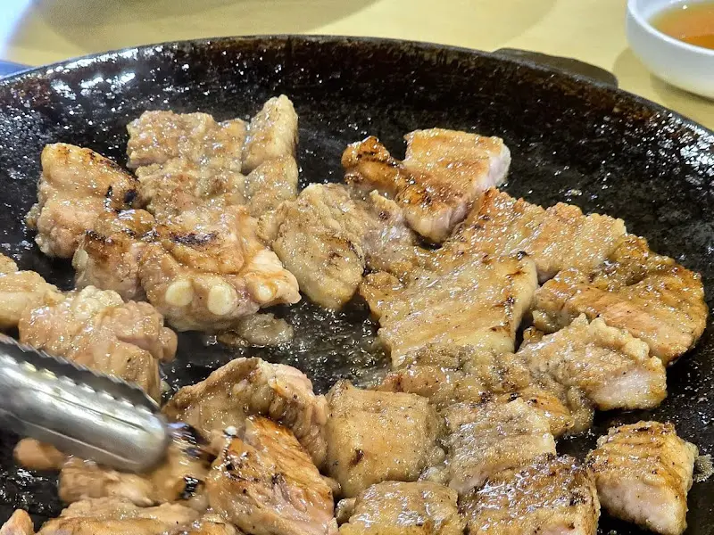 잘 익은 오겹살이 불판 위에 놓여있는 모습