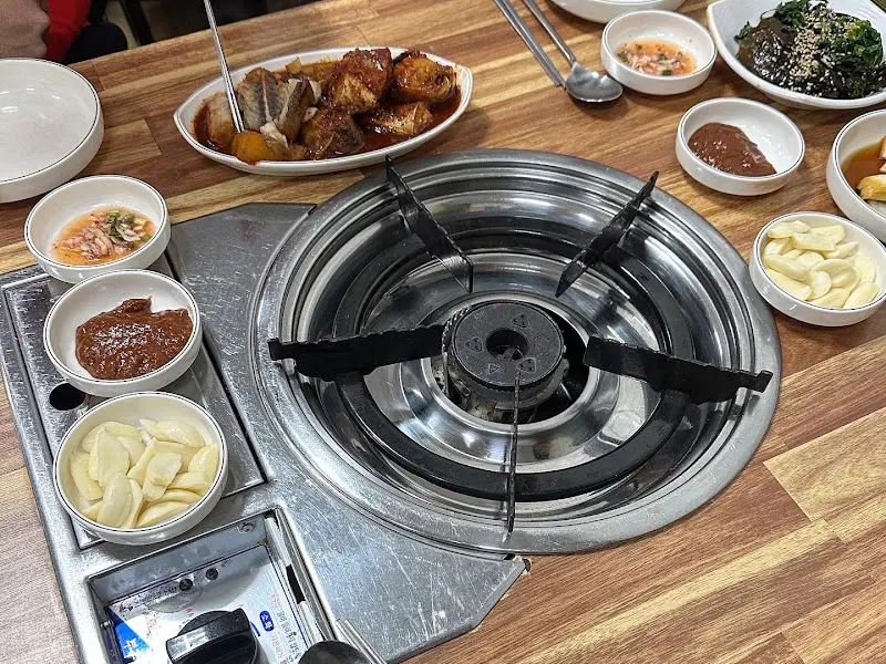 테이블 위 가스 버너와 다양한 곁들임 메뉴들