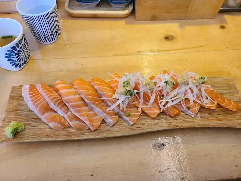 나무 도마 위에 줄지어 놓인 신선한 연어 초밥