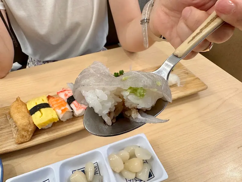 숟가락 위에 올려진 신선한 흰 살 생선 초밥