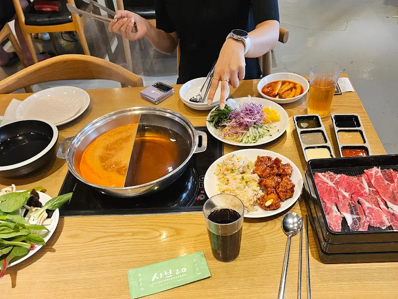 테이블 위에 놓인 샤브샤브 냄비와 다양한 음식들