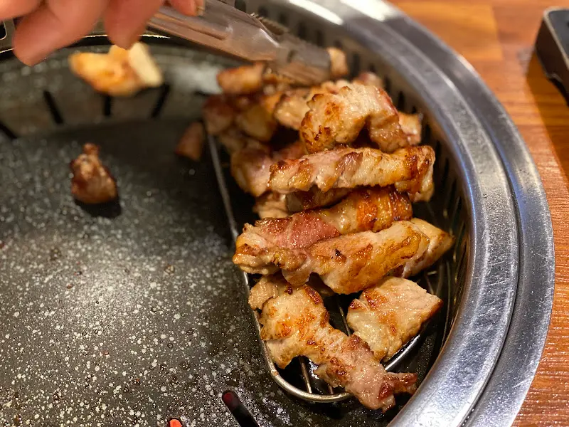 잘 구워진 삼겹살을 집게로 옮기는 모습