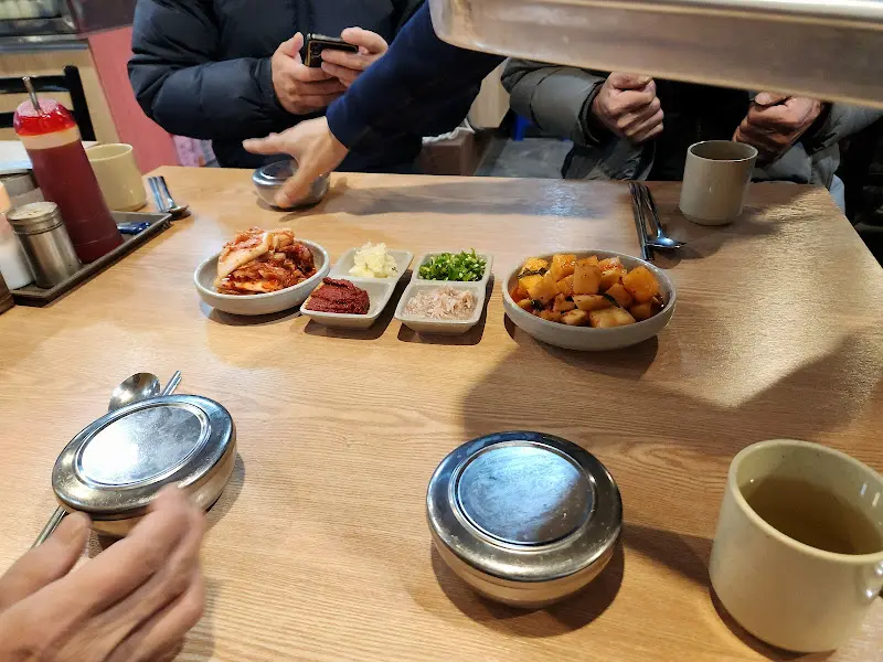 깔끔하게 정돈된 테이블과 깍두기, 김치, 다진 마늘 등 밑반찬이 놓여 있는 모습