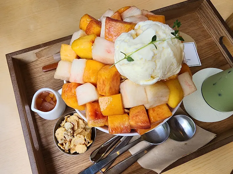 복숭아 빙수 사진. 복숭아가 큐브 형태로 썰어져 있고, 아이스크림과 시럽, 콘푸레이크가 함께 나온다.