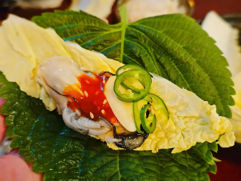 굴, 김치, 마늘, 고추를 곁들여 쌈으로 즐기는 굴보쌈