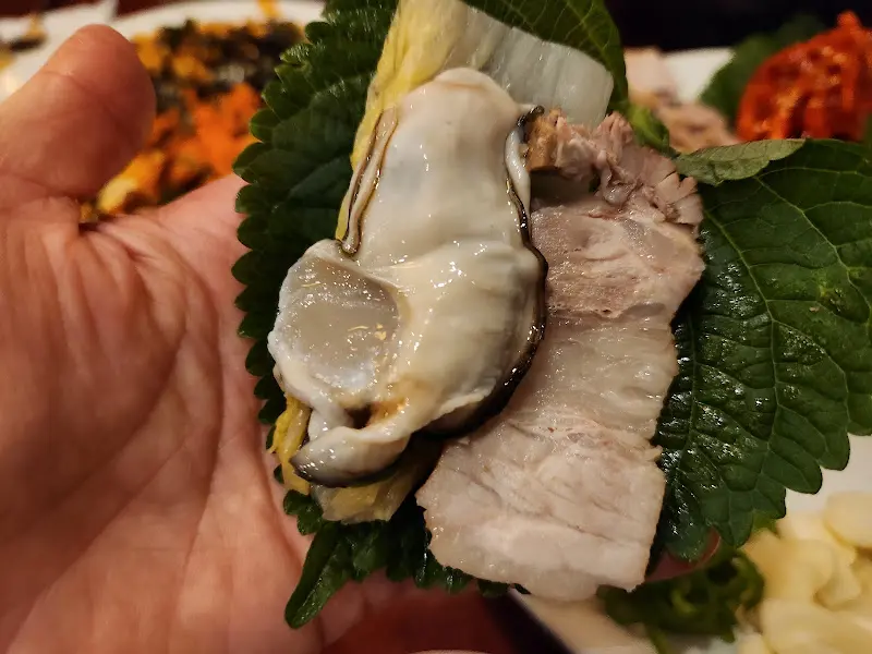 손 위에 올려진 굴보쌈 쌈