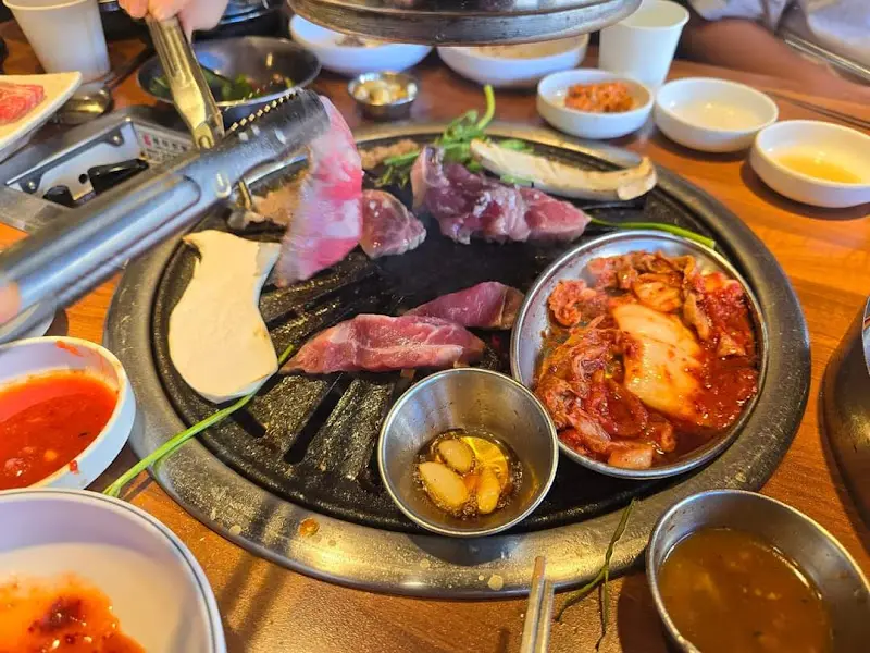 불판 위에 올려진 고기와 김치, 버섯