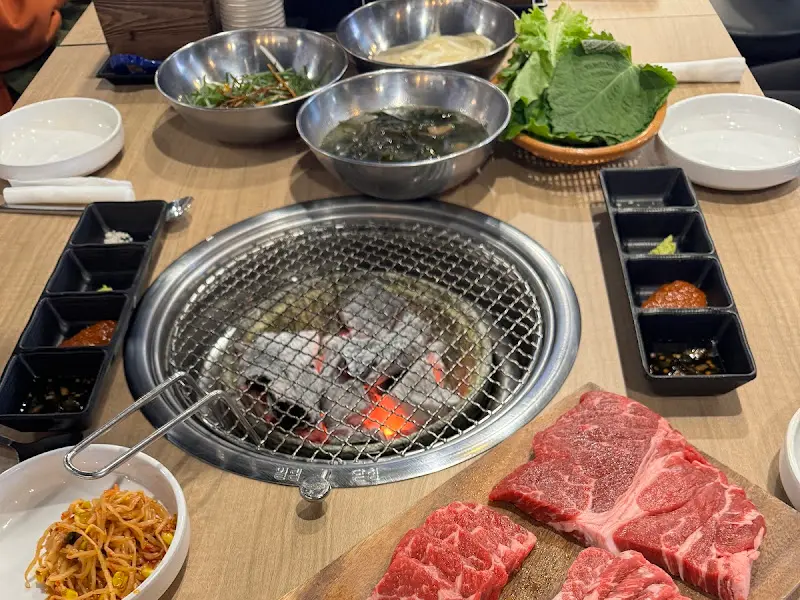 숯불과 고기, 밑반찬이 놓인 테이블 전경