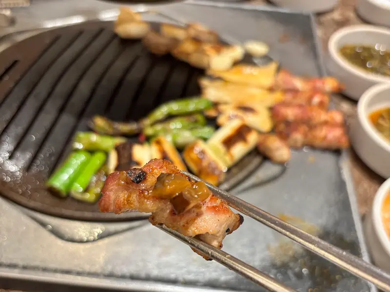 잘 익은 삼겹살을 젓가락으로 집는 모습