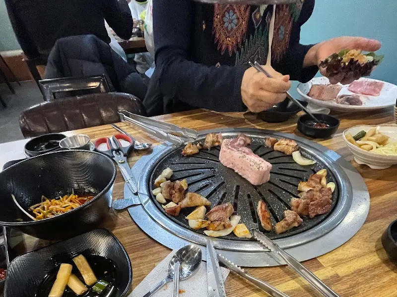 불판 위에서 맛있게 익어가는 삼겹살과 마늘, 양파의 조화