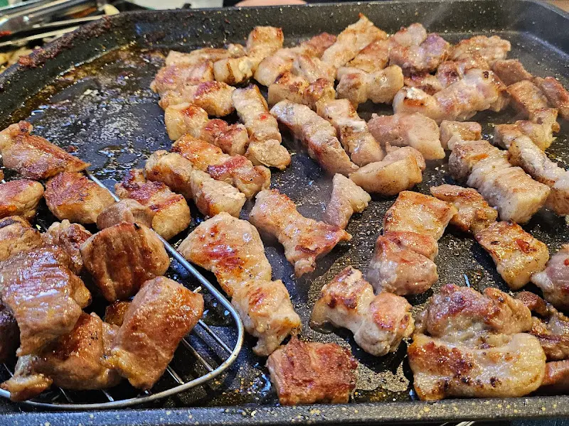 불판 위에서 노릇하게 구워진 초벌 삼겹살