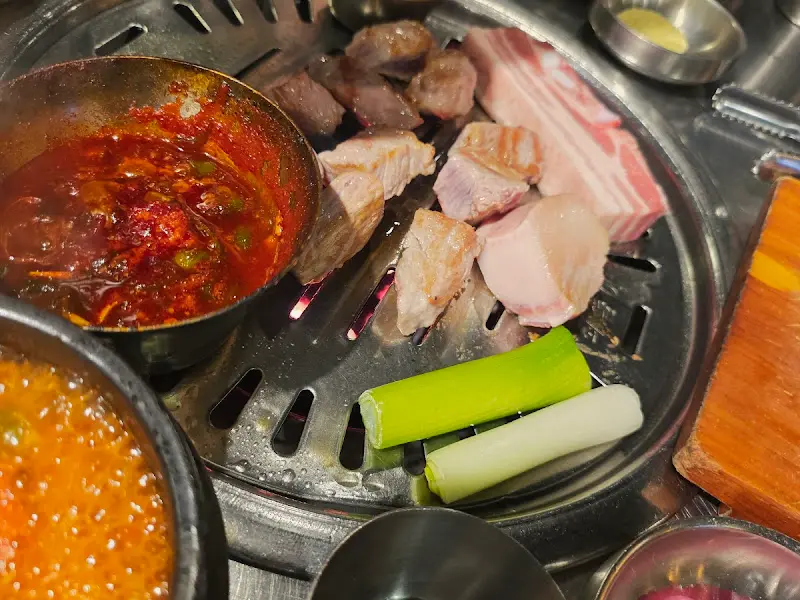 불판 위에서 익어가는 흑돼지 오겹살과 멜젓