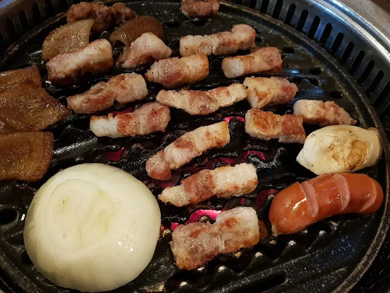 불판 위에서 익어가는 삼겹살, 양파, 소세지