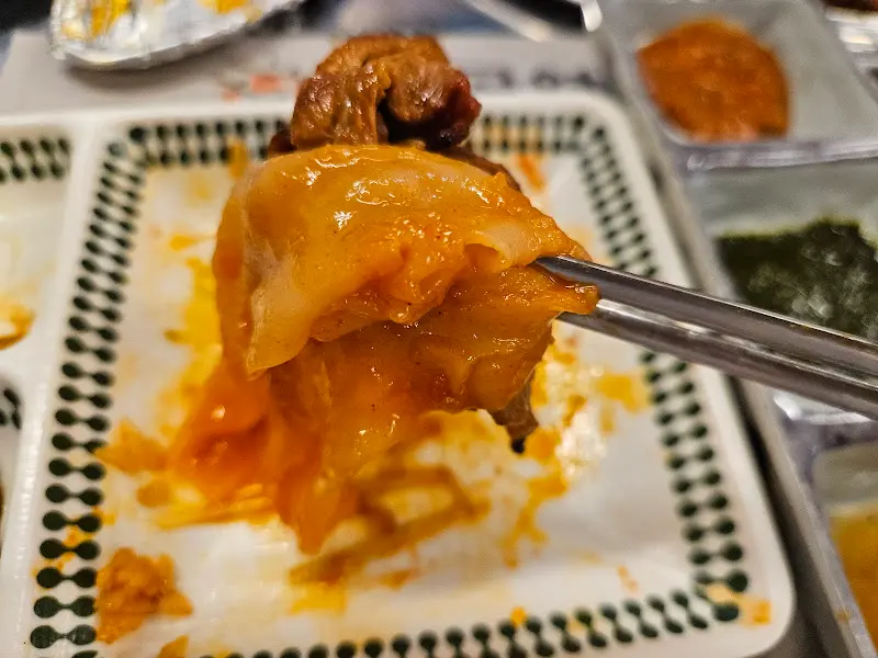 잘 익은 고기를 김치에 싸서 먹는 모습