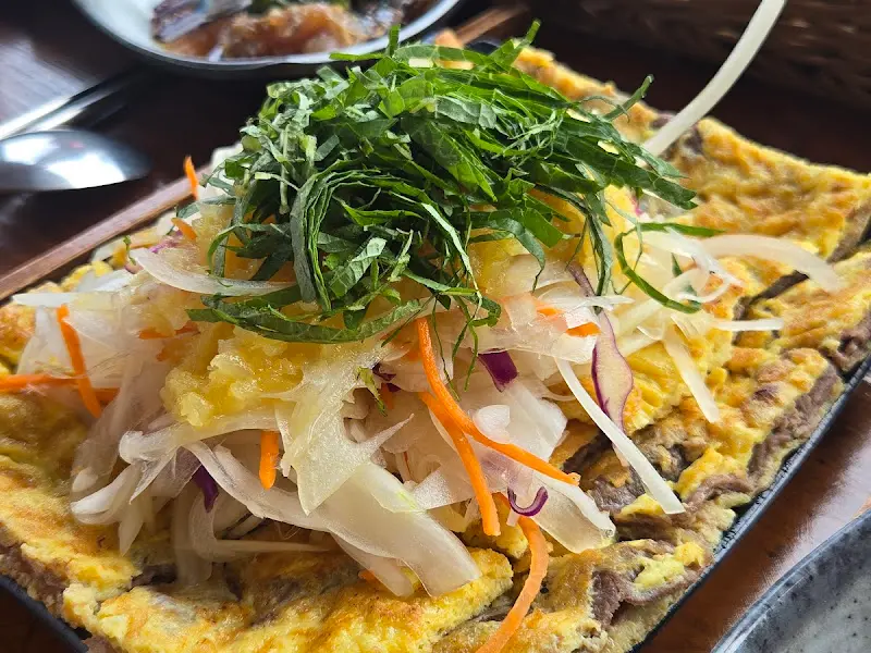 육전 위에 양파 샐러드와 채소가 소복하게 쌓여 있는 모습