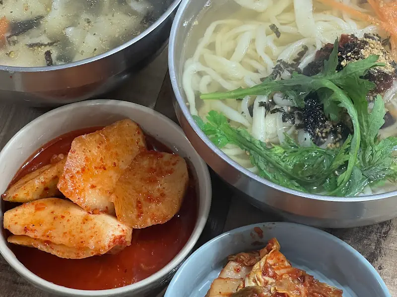 테이블 위에 놓인 칼국수, 김치, 석박지