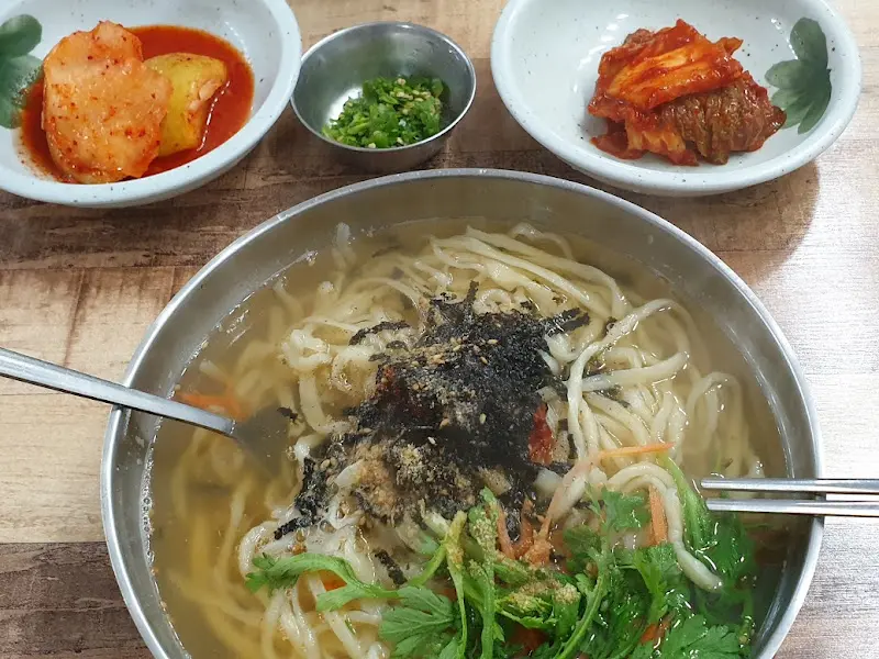 칼국수, 김치, 석박지가 놓인 테이블 전체 샷