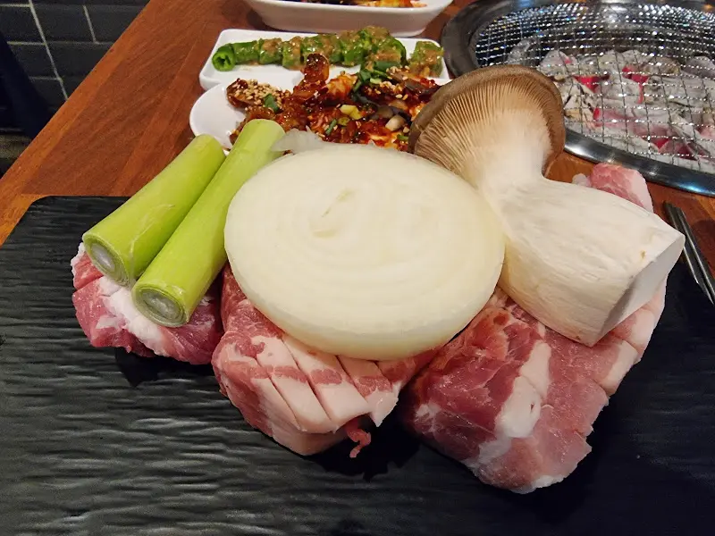 솥뚜껑에 삼겹살, 버섯, 양파를 올려 구워먹는 모습