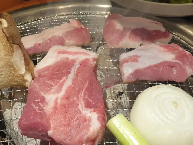 솥뚜껑에 올려진 삼겹살과 양파