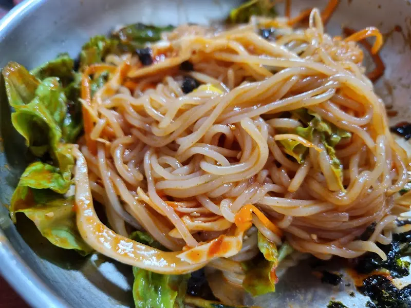 양념에 비벼진 쫄면의 모습. 면발이 쫄깃해 보이고, 양념이 맛있게 버무려져 있다.