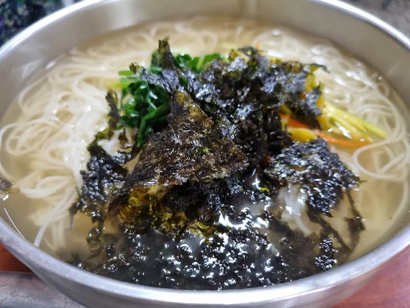 잔치국수 위에 김가루와 야채가 올려져 있는 모습. 따뜻하고 푸짐해 보인다.