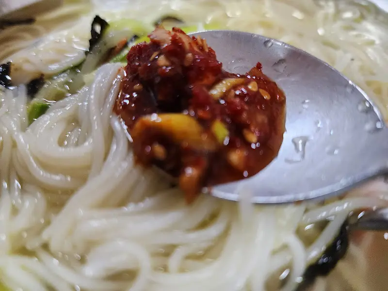 숟가락 위에 올려진 잔치국수와 양념장의 모습. 함께 먹으면 더욱 맛있을 것 같다.