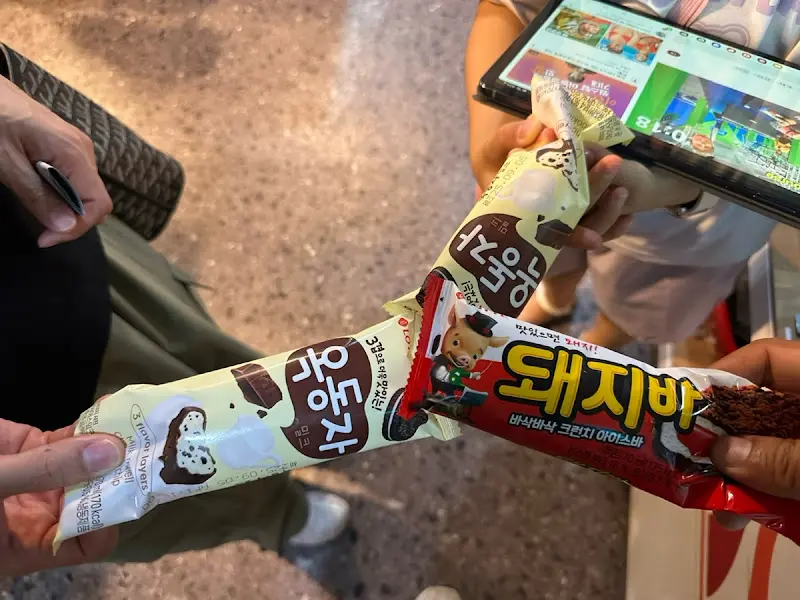 가게 앞에 놓인 아이스크림 냉장고와 아이스크림을 고르는 사람들