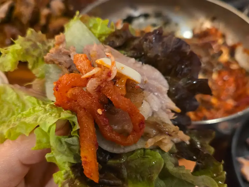 싱싱한 쌈 채소에 족발과 매콤한 무말랭이를 올려 한 입 가득