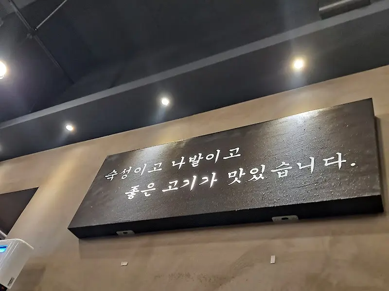 식당 벽면에 쓰여 있는 문구 '숙성이고 나발이고 좋은 고기가 맛있습니다'