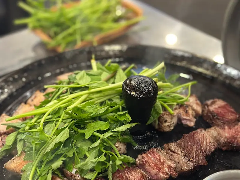 불판 위에 올려진 미나리와 고기의 조화