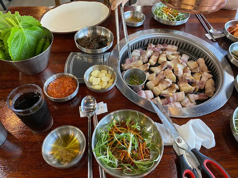 다채로운 밑반찬과 흑돼지 오겹살이 푸짐하게 차려진 테이블