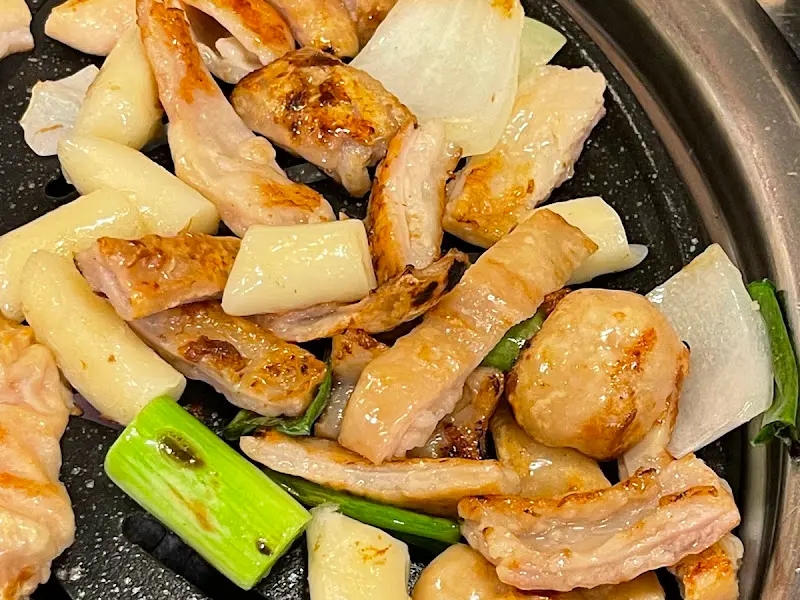 불판 위에서 노릇하게 구워진 막창과 떡, 양파