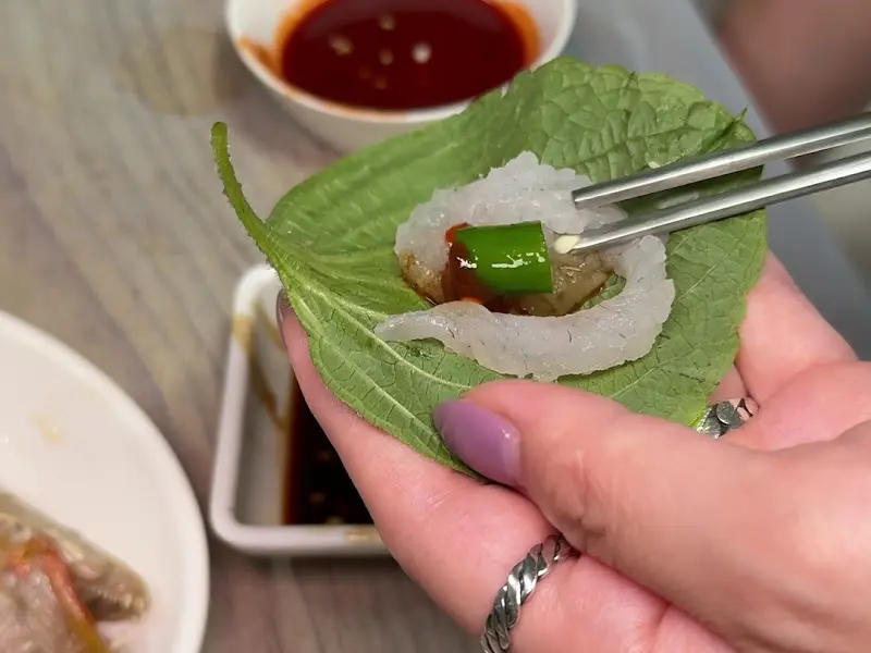 싱싱한 회 한 점을 깻잎에 싸 먹는 모습