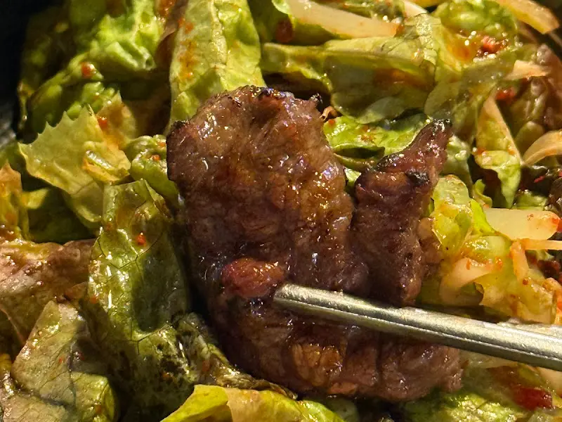잘 구워진 소갈비살을 쌈채소와 함께 먹는 모습