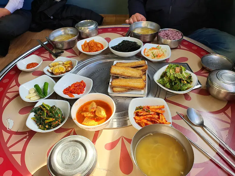 다양한 밑반찬과 초벌 삼겹살이 한 상 가득 차려진 모습