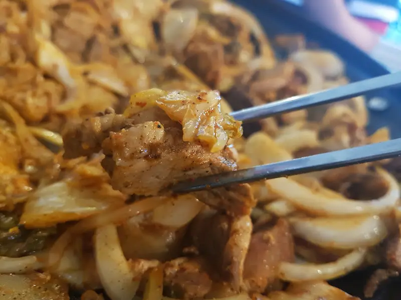 젓가락으로 집어 올린 돼지고기와 김치