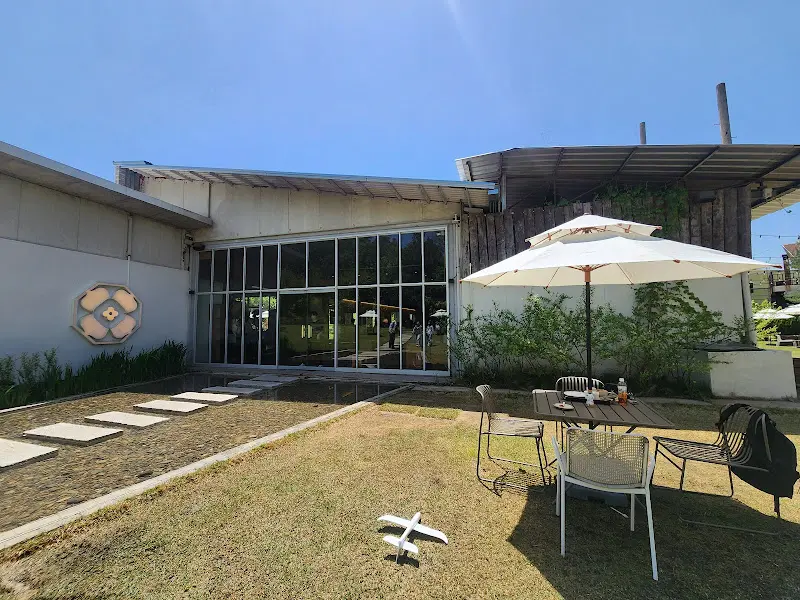 푸른 하늘 아래 넓은 잔디밭과 테이블이 놓여진 명주정원의 외부 전경