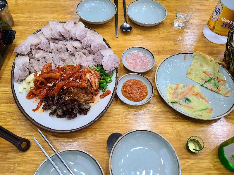 보쌈, 김치, 떡만두국, 전이 함께 나오는 한 상 차림 사진