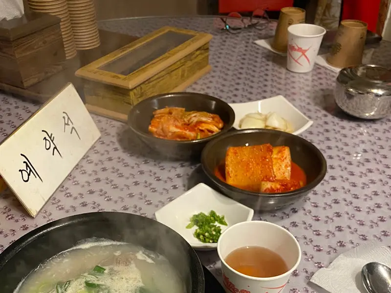 테이블 위에 놓인 곰탕, 김치, 깍두기