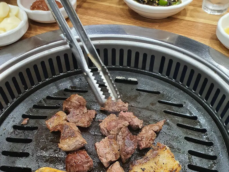 잘 익은 고기를 집게로 들어올리는 모습