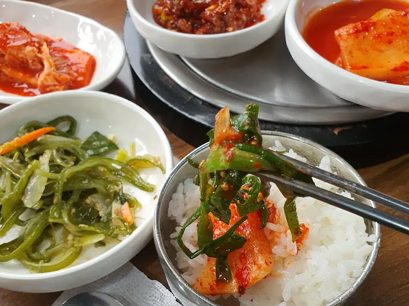 밥 위에 김치와 나물을 올려 먹는 모습