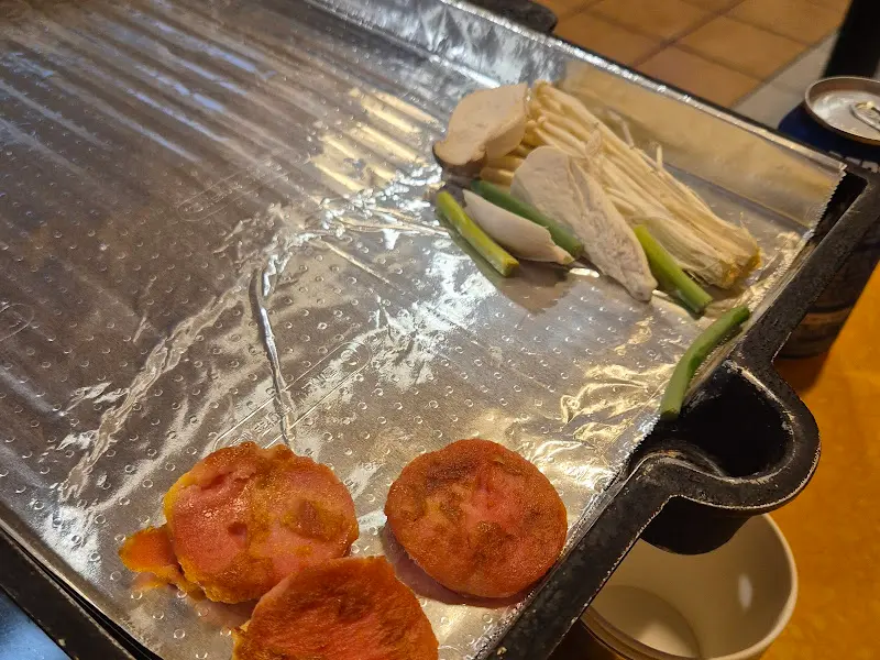 불판 위에 구워지고 있는 김치, 버섯, 냉삼