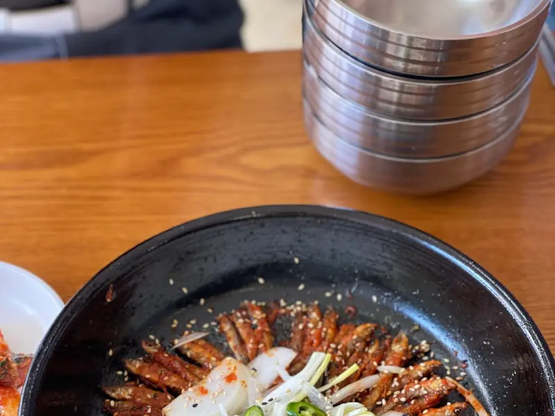 테이블 위에 놓인 도리뱅뱅이 클로즈업 되어 있다. 윤기가 흐르는 잡어 위에 양파와 파가 올려져 있어 식감을 자극한다.