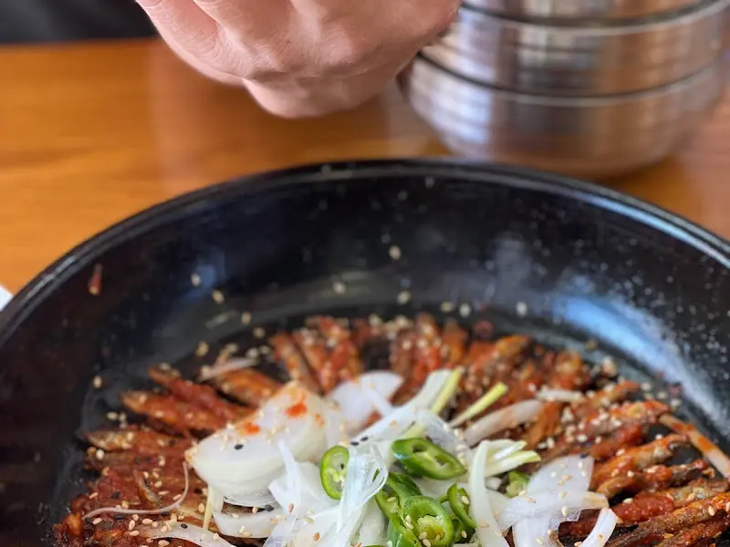 접시에 담긴 도리뱅뱅을 젓가락으로 집어 올리는 모습이 담겨있다. 겉은 바삭하고 속은 촉촉해 보인다.