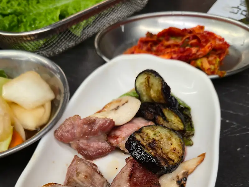 잘 구워진 흑돼지와 밑반찬, 쌈 채소가 어우러진 모습