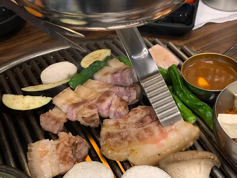 불판 위에서 맛있게 익어가는 돼지고기와 채소들