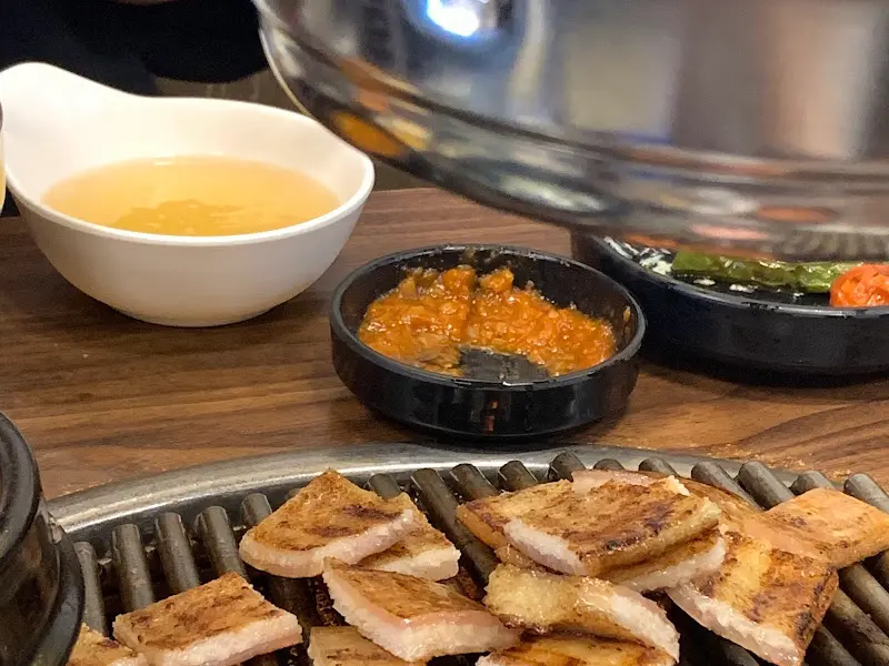 잘 구워진 돼지 껍데기를 멜젓에 찍어먹는 모습