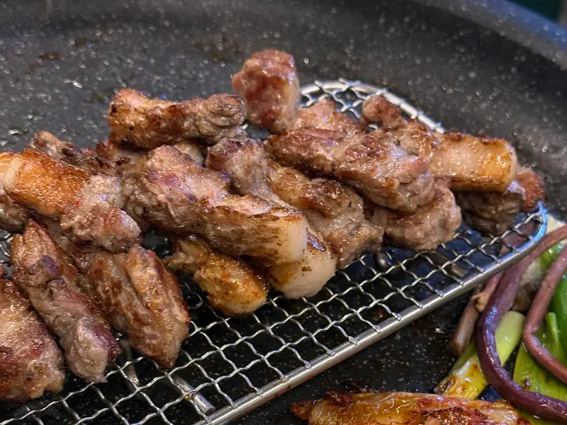 잘 구워진 삼겹살을 망 위에 올려놓은 근접 사진